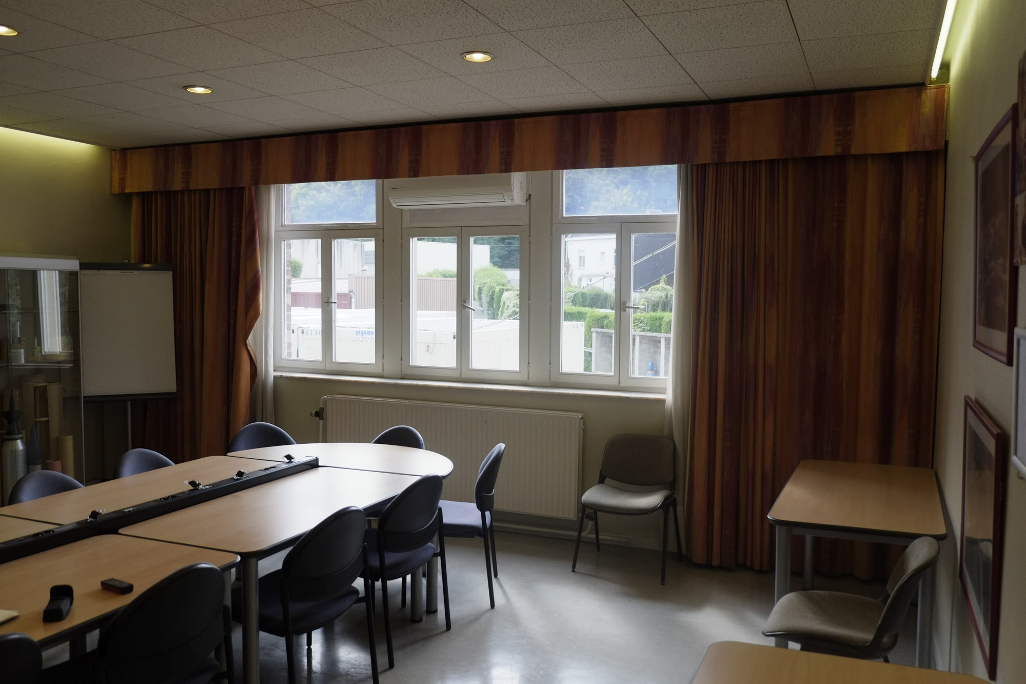 Salle de réunion avant rénovation dans une entreprise du bassin liégeois – espace standard avec mobilier modulaire et plafond technique