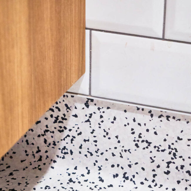 Détail de finition du sol en linoléum avec remontée de plinthe à gorge - arrondie - dans les sanitaires d’une entreprise du bassin liégeois