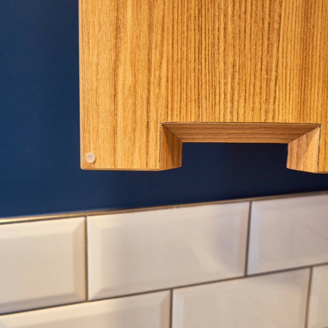Poignée intégrée biseautée dans une armoire sur mesure en stratifié – détail de menuiserie dans les sanitaires d’une entreprise à Liège