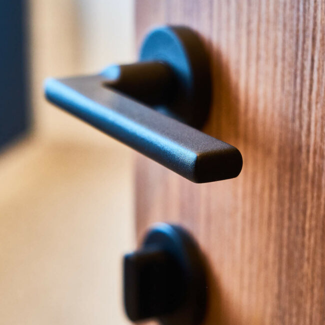 Détail de la poignée de porte noire des WC dans les sanitaires d’une entreprise à Liège