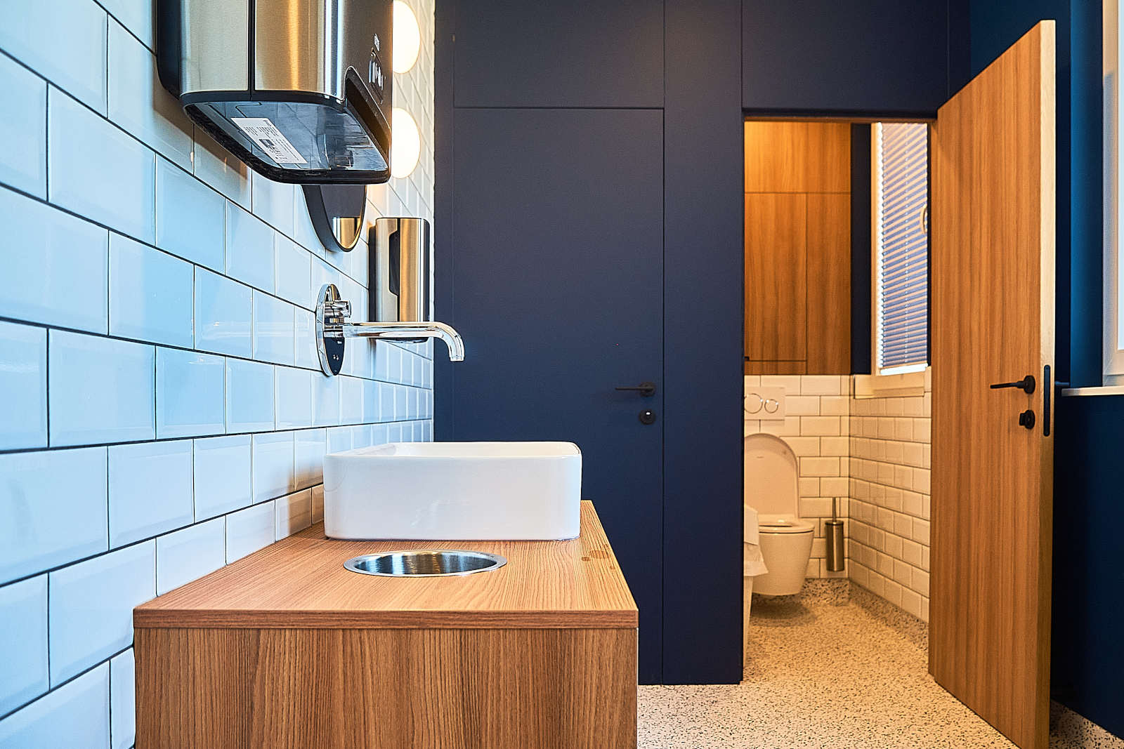 Sanitaires réalisés d’une entreprise à Liège – aménagement intérieur avec meuble en bois et carrelage métro blanc