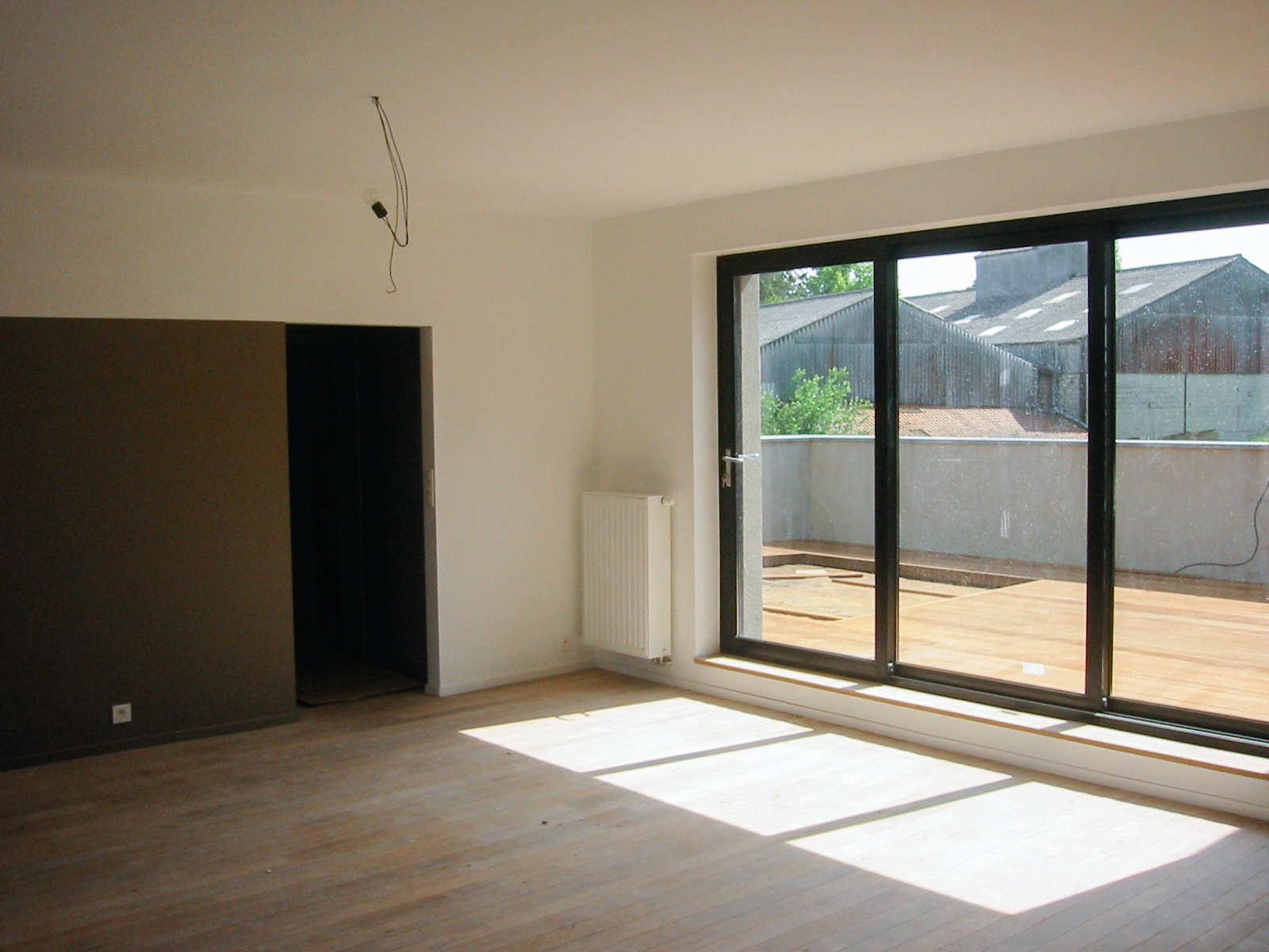 Séjour lumineux de l’appartement du premier étage avec grande baie vitrée donnant sur la terrasse